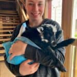 Girl holding a black baby rescue goat