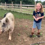 A smiling kid walking next to a rescue pig